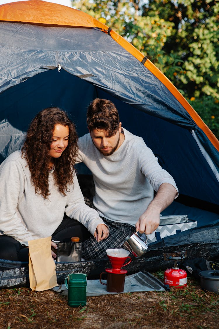 Young Couple Brewing Pour Over Coffee In Camping Tent