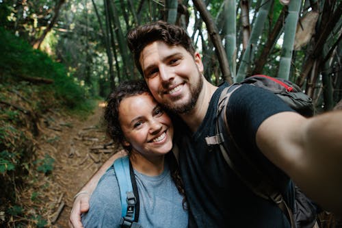 Free Happy couple of travelers taking selfie in forest Stock Photo