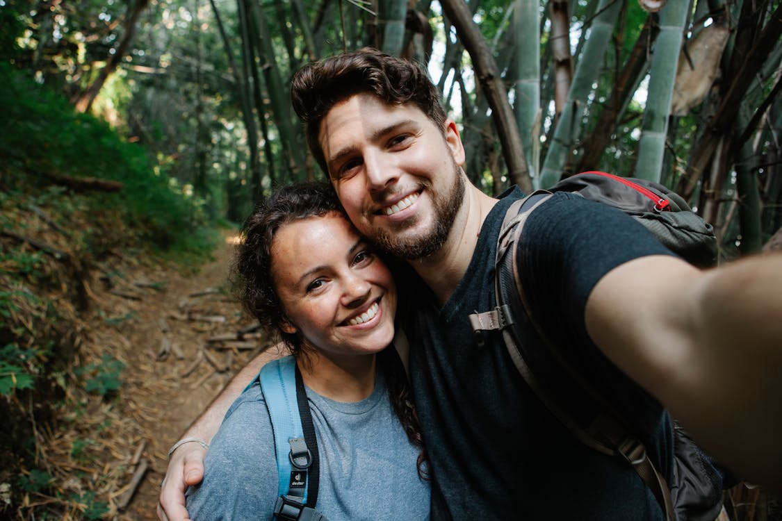 Happy couple of travelers taking selfie in forest