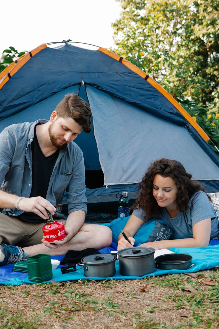 Couple Of Hikers Preparing Food In Nature Near Tent