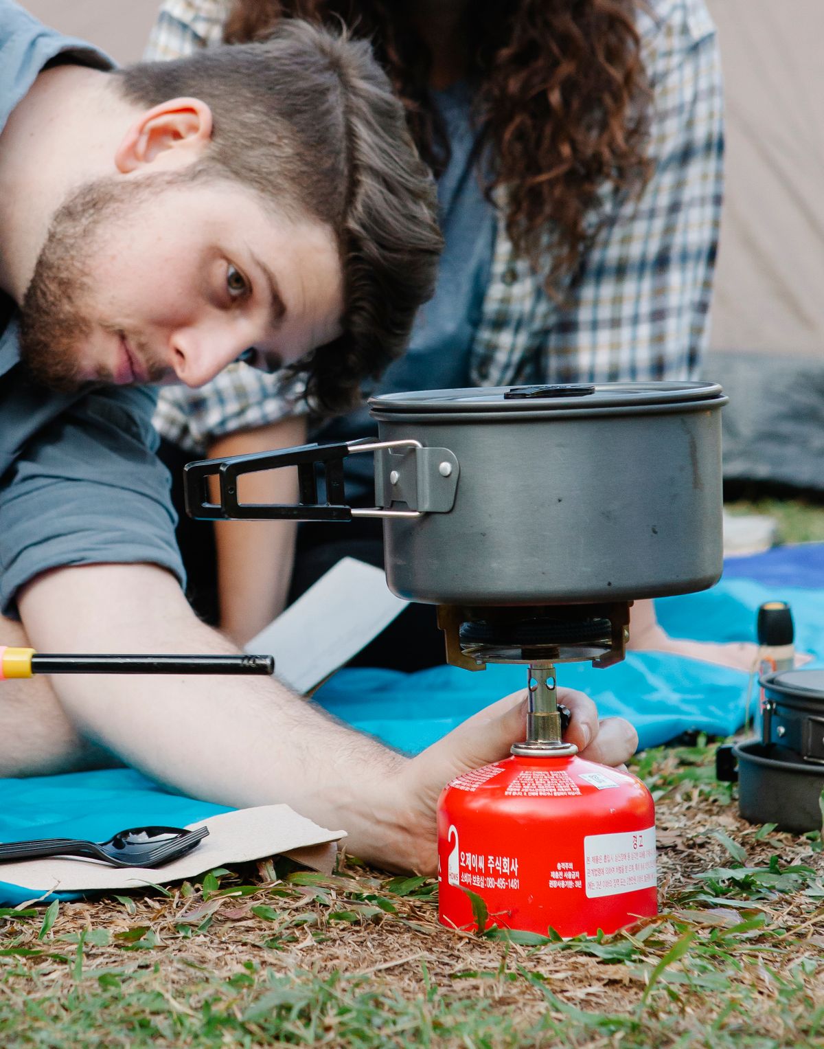 Traveler preparing food on a compact camping stove outdoors