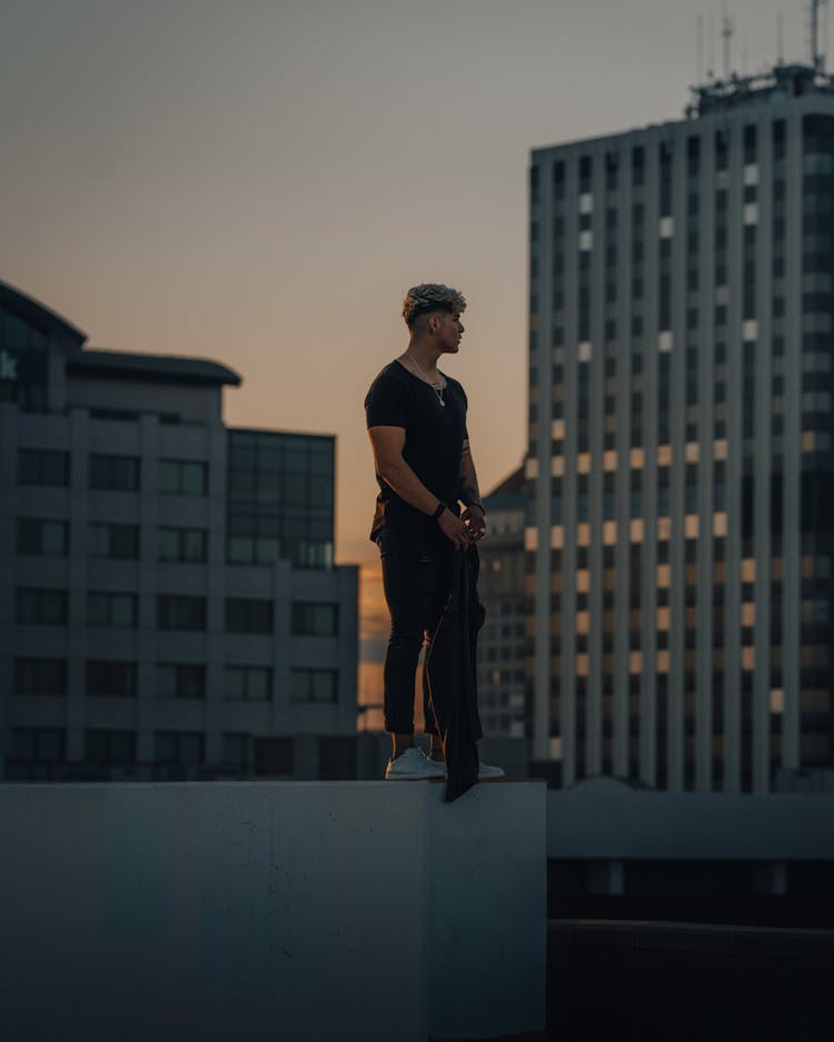 Man In Black Shirt And Pants Standing On Edge Of The Building 