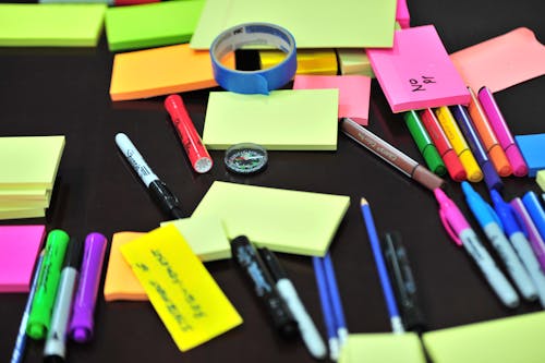 Photo of Sticky Notes and Colored Pens Scrambled on Table