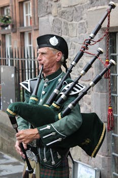 一位穿着传统苏格兰制服的老人，在石街上吹着风笛