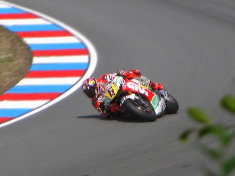 Motorcycle racer leans into a sharp curve on a high-speed track during a competition.