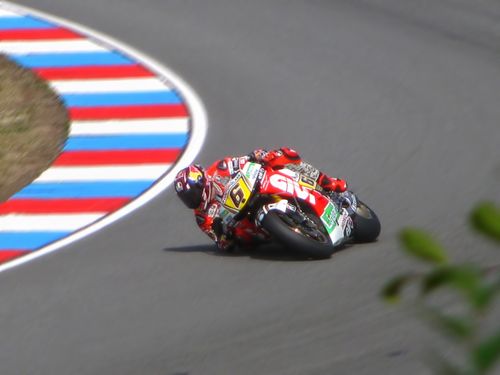 Free Motorcycle racer leans into a sharp curve on a high-speed track during a competition. Stock Photo