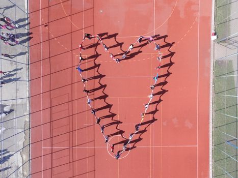 People forming a heart shape on a sports court in Timișoara, Romania. Aerial view.