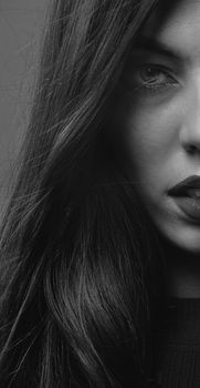 Striking black-and-white half face portrait of a woman with long dark hair.