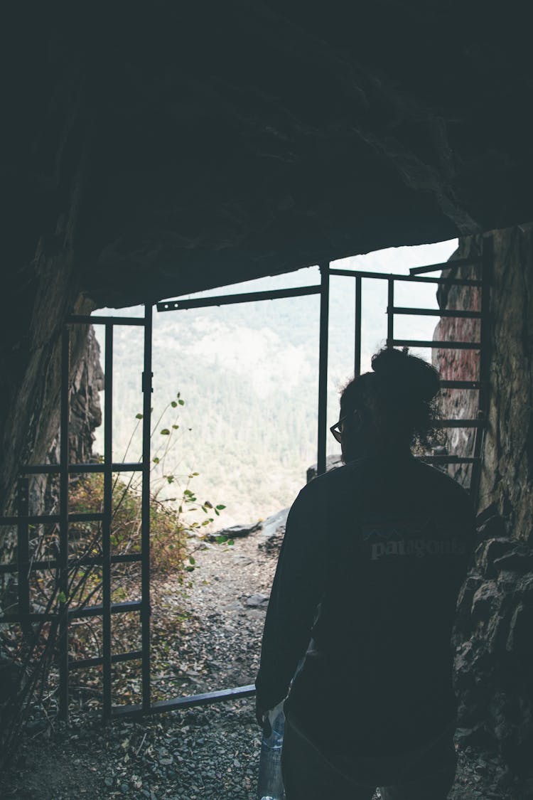 Silhouette Of Man Standing Near The Cave Gate 