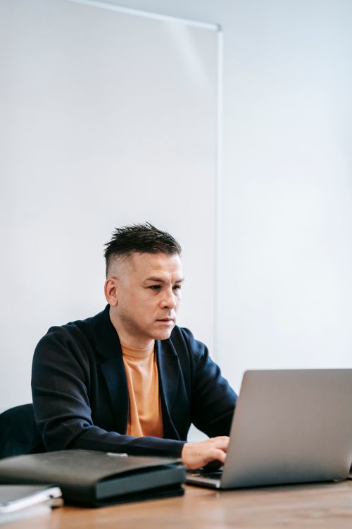 Free Man working intently on a laptop in a modern home office setting. Stock Photo
