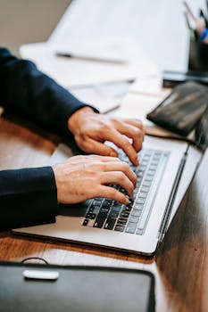 Close-up of a professional typing on a laptop indoors, highlighting remote work and technology.