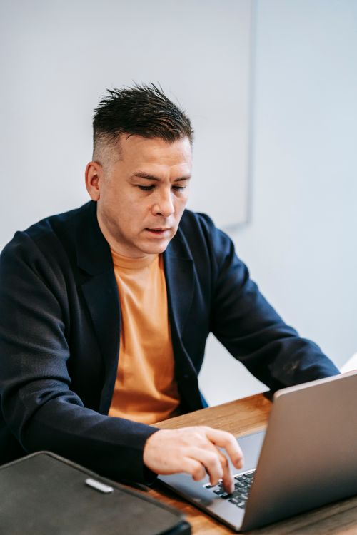 Free A man deeply engaged in work on a laptop at a home office setting, portraying concentration and professionalism. Stock Photo