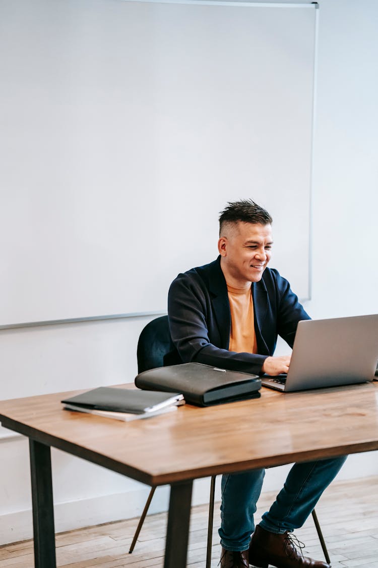 Photo Of Man Smiling In Front Of His Laptop