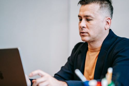 Free A focused professional man working on his laptop indoors in a modern setting. Stock Photo