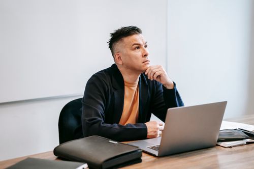 Free Thoughtful man working on a laptop in an office setting, engaged in remote work. Stock Photo