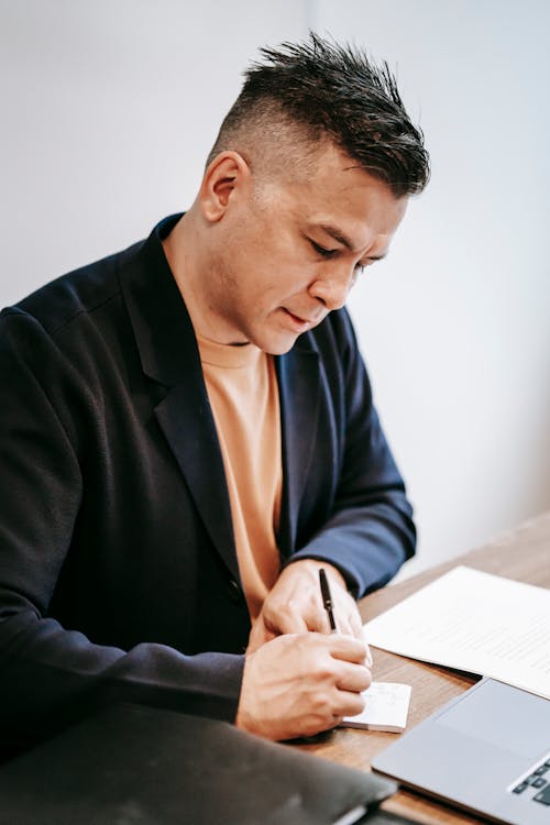 Photo Of Man Writing On A Piece Of Paper