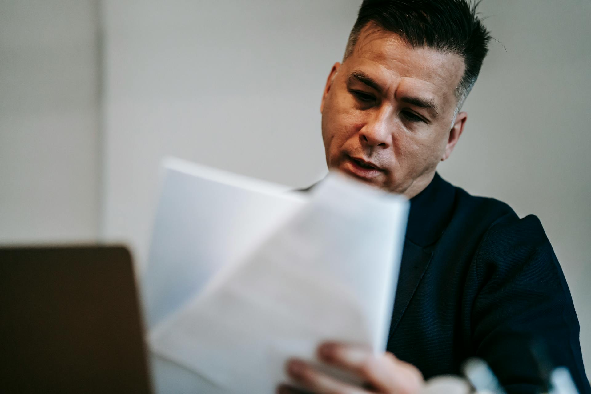 Professional man intently reviewing paperwork at his workstation indoors.