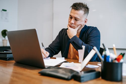 Photo Of Man Writing On Piece Of Paper