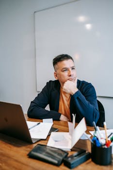 A man sits thoughtfully at a home office desk, embodying remote work contemplation.