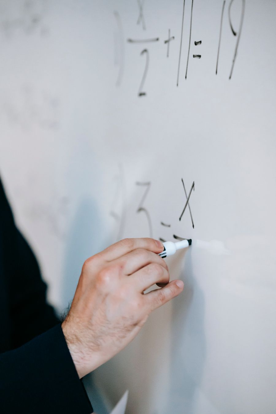 Educator solving equations on a whiteboard