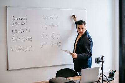 Instructor writing equations across a classroom whiteboard. Photo by Vanessa Garcia on Pexels
