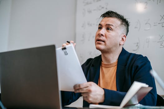 Educator discussing concepts during an online session, sitting at a desk with a laptop.