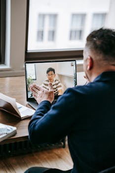Business professional having a video call at the office with a colleague using a laptop.