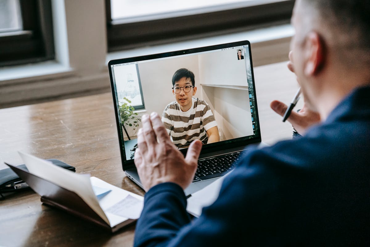 Person recording a budgeting video on a smartphone at a desk with a laptop