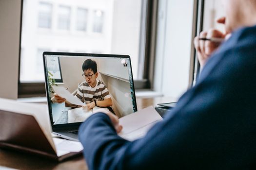 Two people engaged in an online class discussion through a video call on a laptop.