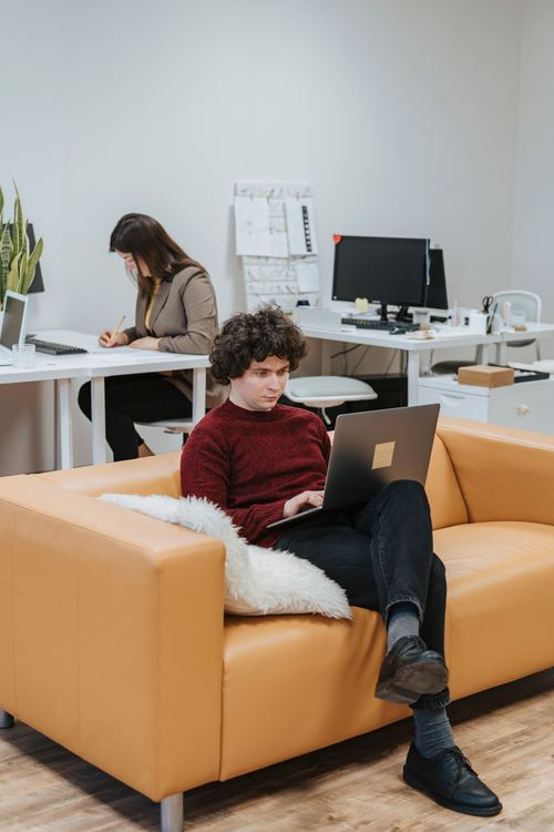 Free Two colleagues in a modern office setting working intently on projects, highlighting productivity. Stock Photo