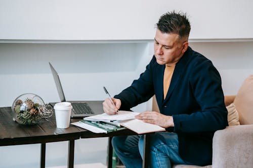 Homme En Blazer Bleu Tenant Un Stylo écrit Sur Papier Blanc