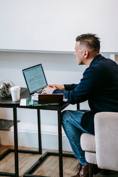 A man focused on remote work with a laptop at a home office setting.