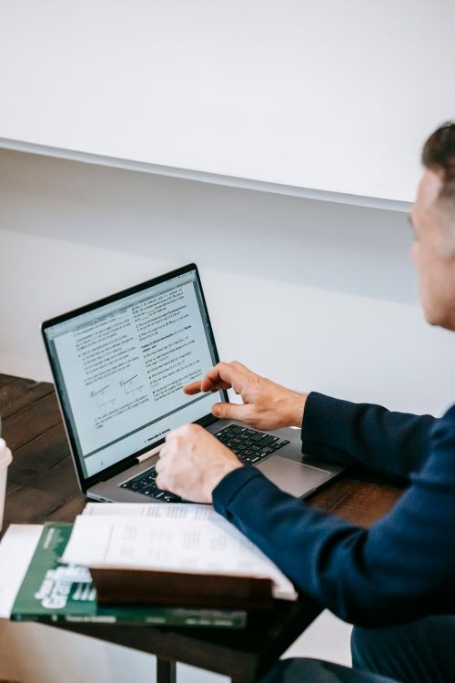 Free Person focused on work at home office desk with laptop and documents, representing modern remote work culture. Stock Photo
