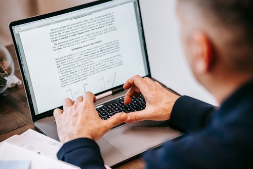 Photo Of Person Using Laptop On Wooden Table