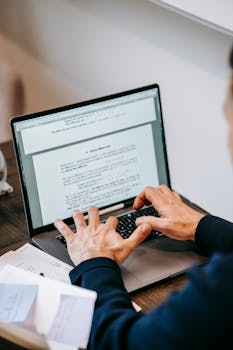 Close-up of hands typing on laptop in a home office, symbolizing remote work productivity.