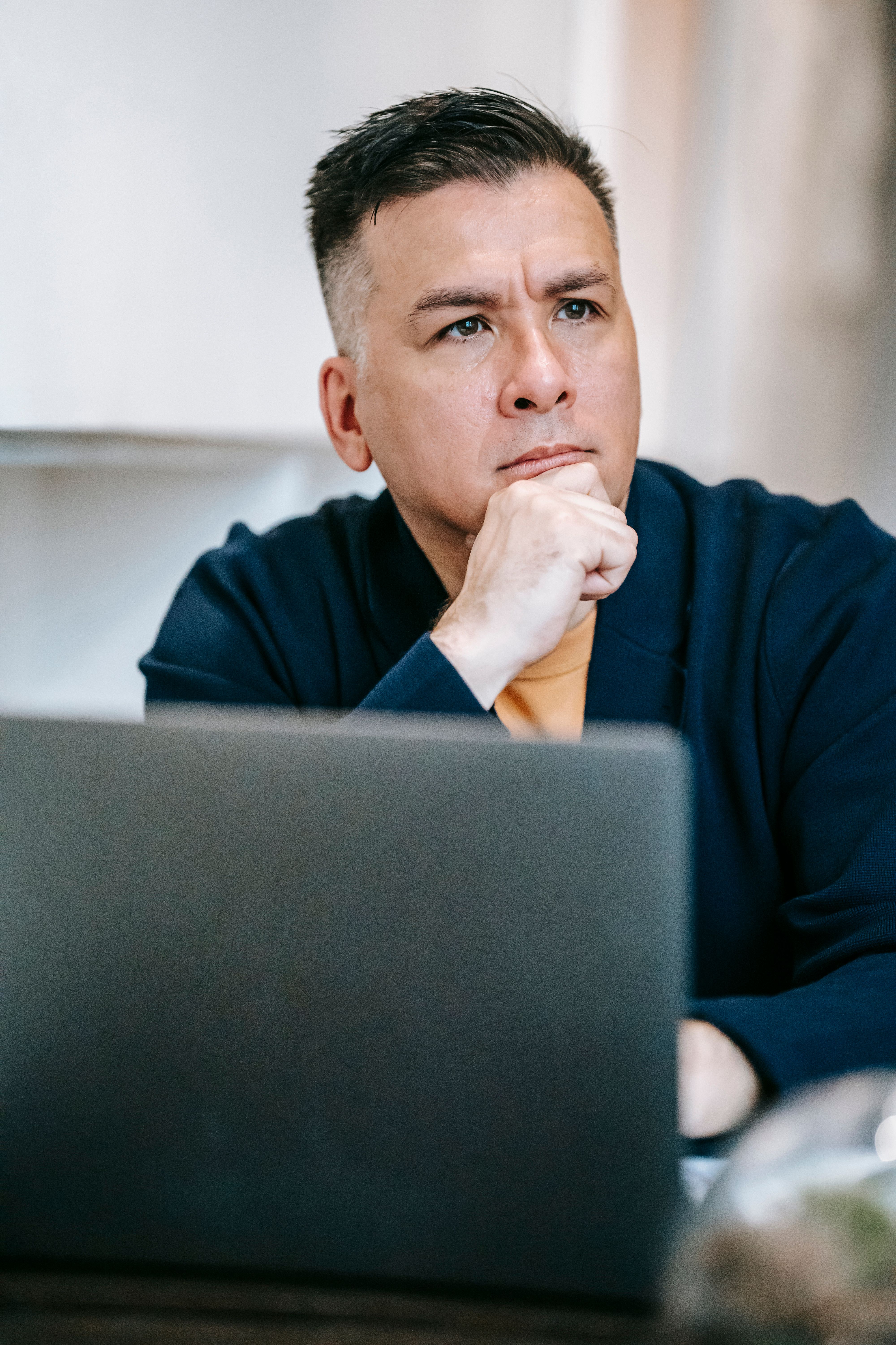 Focused man using a laptop, deep in thought while working from home office.