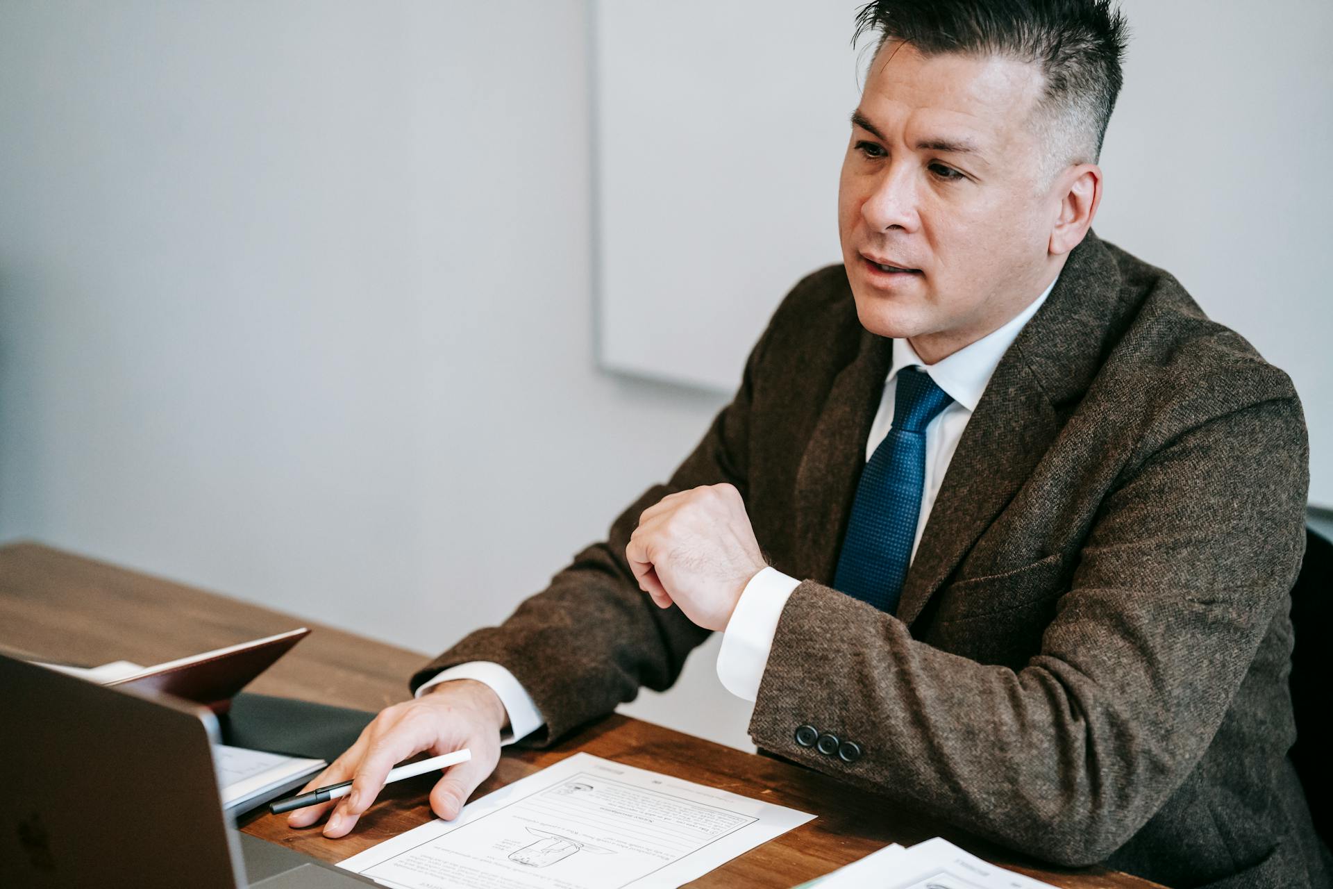 A man in a suit discussing paperwork at his desk, showcasing a professional work environment.