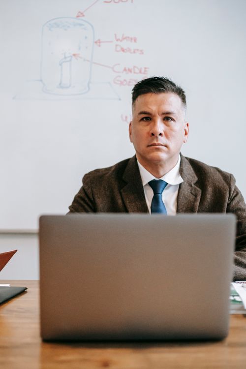 Free Confident man in formal wear working on a laptop in an office environment, conveying focus and professionalism. Stock Photo