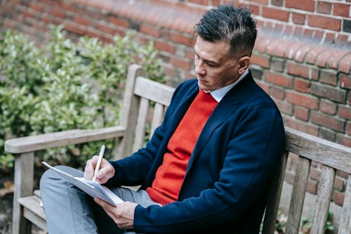 Photo Of Man Sitting On Brown Wooden Bench 