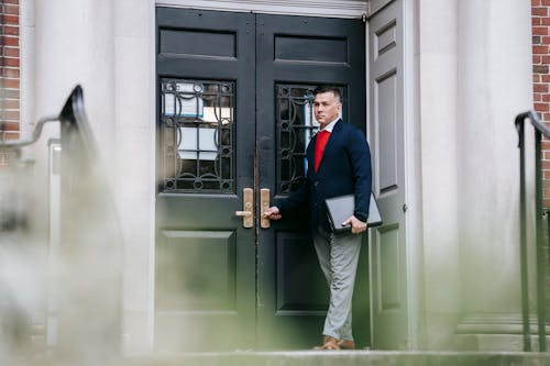 Photo Of Man Standing Beside Wooden Door