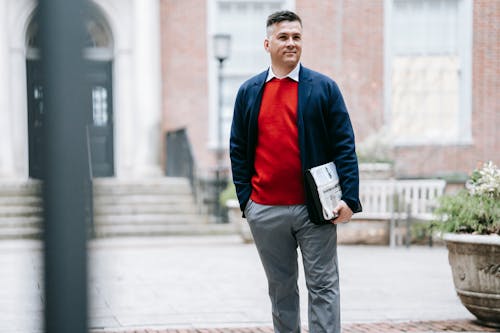 Hombre Con Camisa De Manga Larga Roja Y Azul Y Pantalón Gris Con Libro