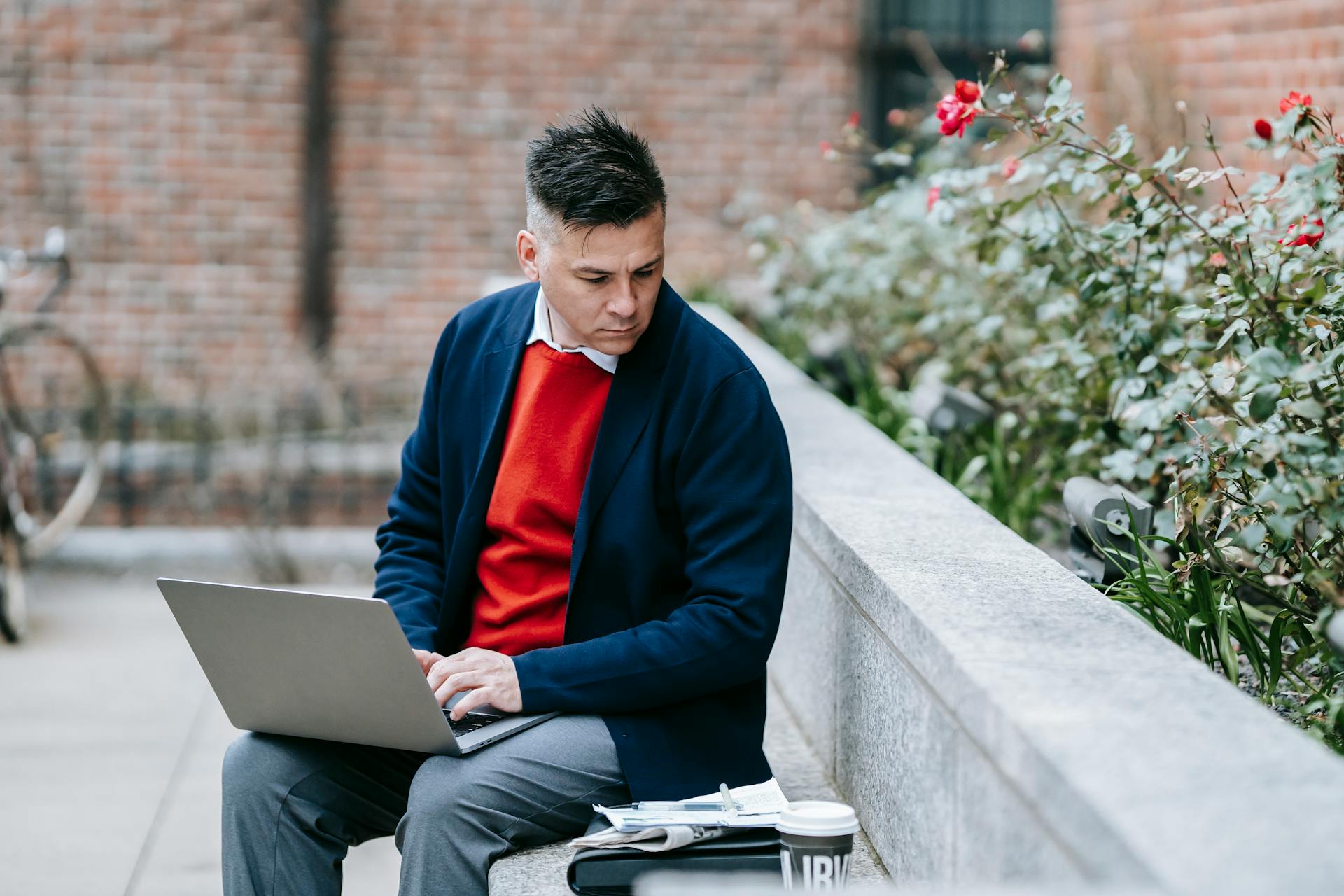 Businessman working remotely on a laptop in an outdoor setting.