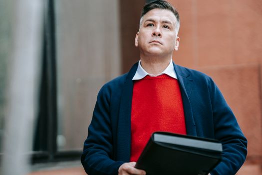 A serious man in stylish attire holds a portfolio, exemplifying modern business professionalism.
