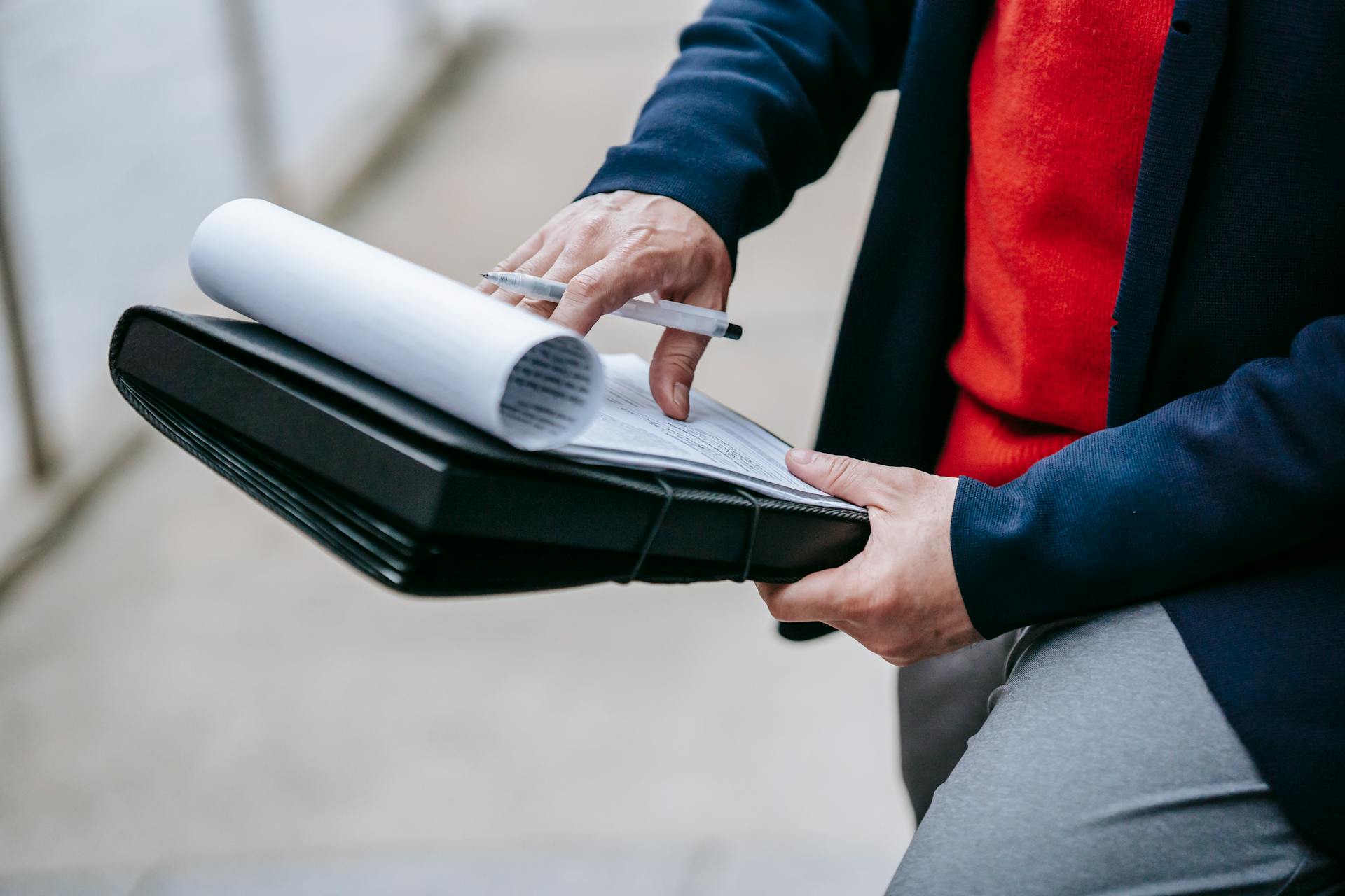 Close-up of a professional person reviewing documents outdoors. Engaged in work with focus on writing materials.