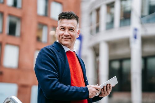 Free Confident adult male using a tablet device in an urban outdoor setting. Stock Photo