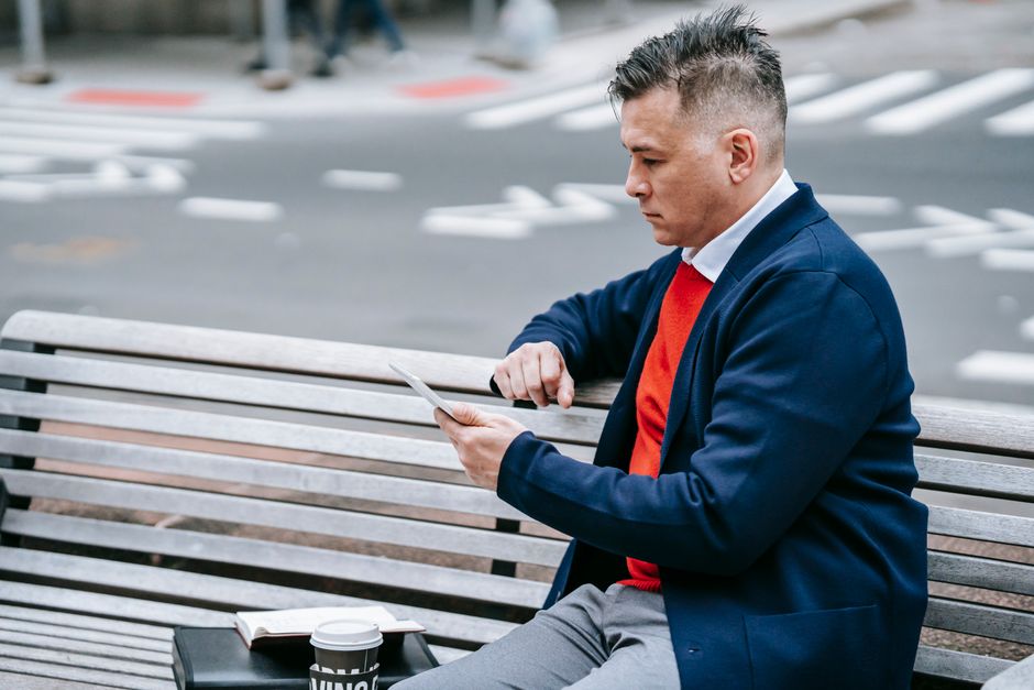Professional man using tablet on a city bench while enjoying outdoor urban environment. Professional man using tablet on a city bench while enjoying outdoor urban environment.