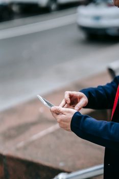 Professional in business attire using a smartphone outdoors, reflecting modern work lifestyle.