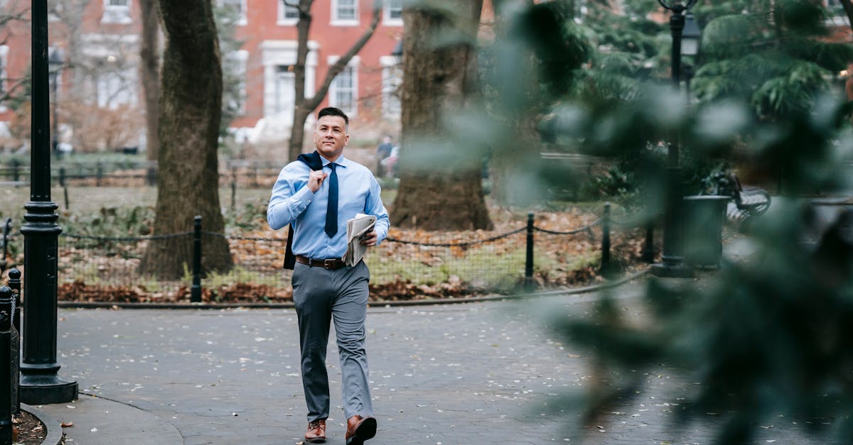 Photo by Vanessa Garcia A stylish man in professional attire confidently walks through a serene urban park.