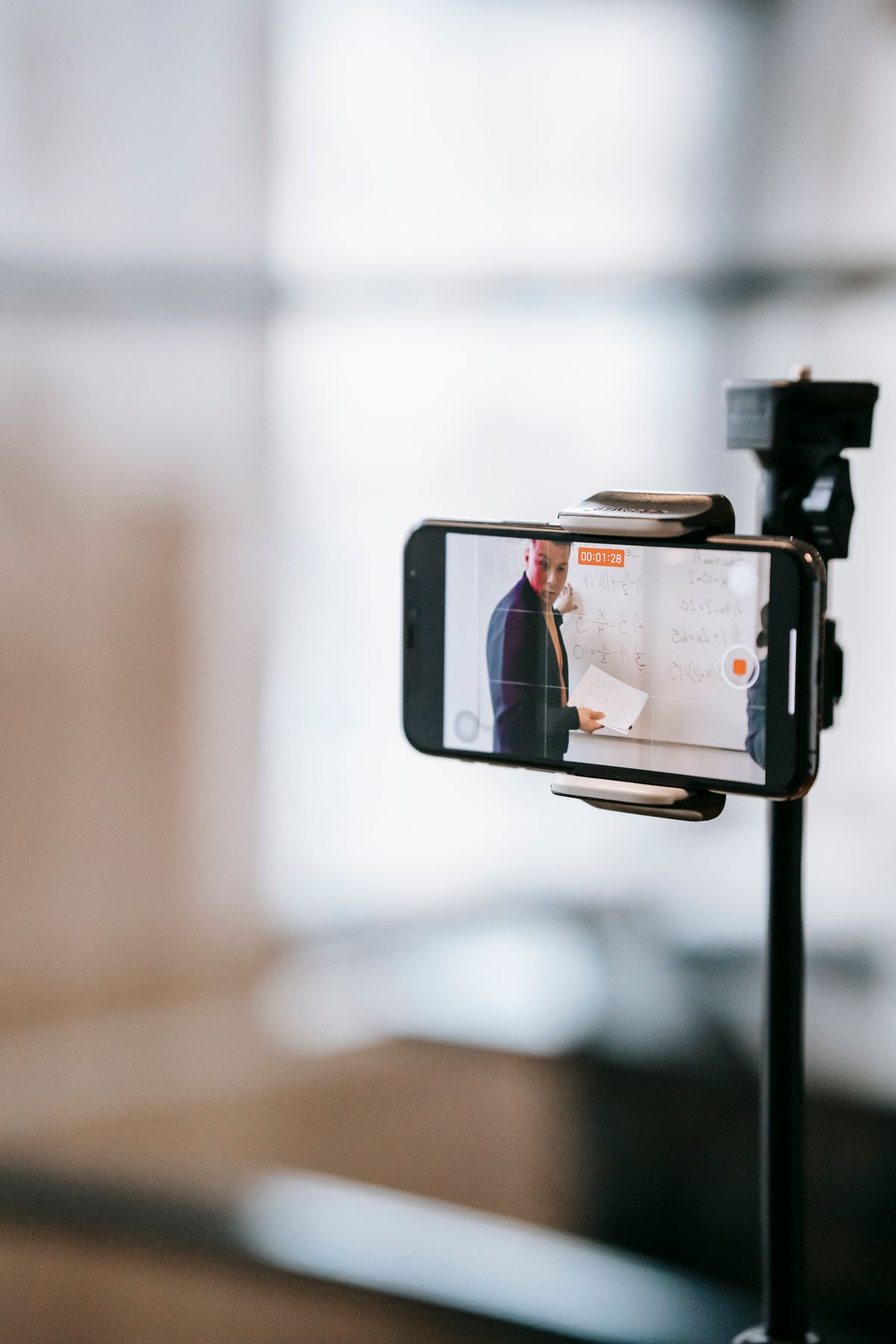 A person setting up a video recording of a presentation at a desk
