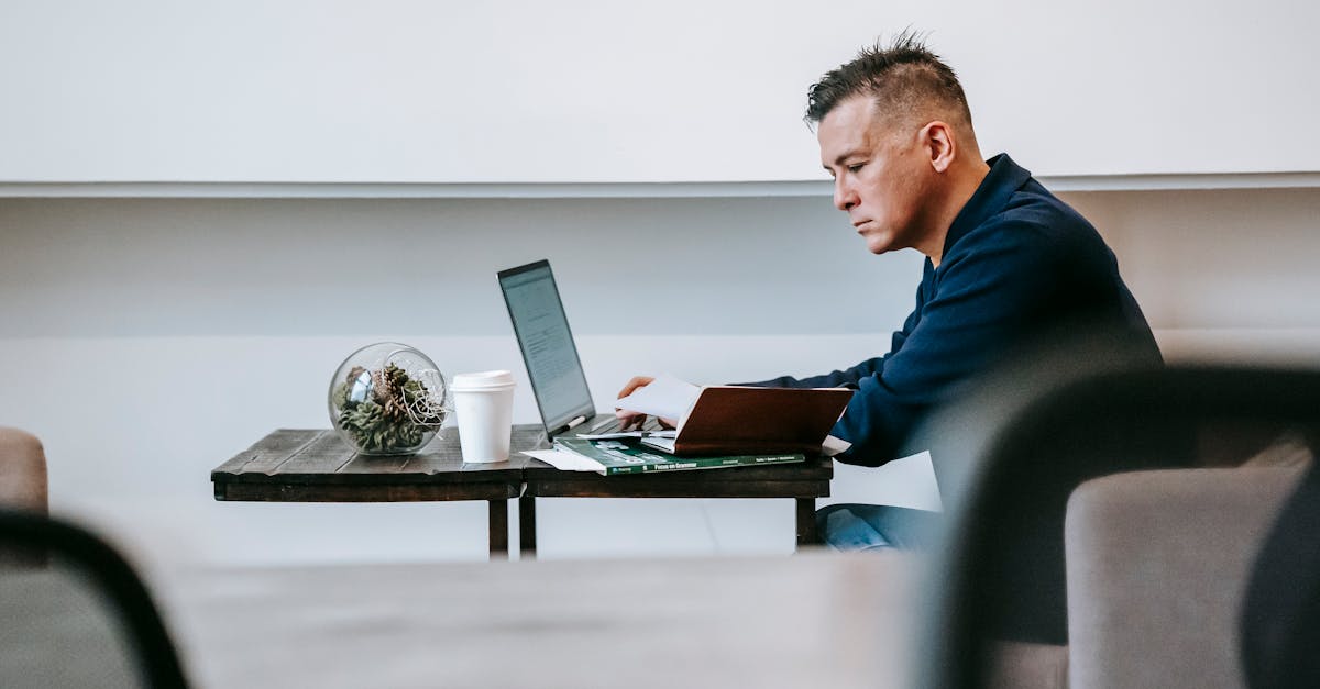 A man intently working on a laptop in a modern office setting, showcasing concentration and professionalism.